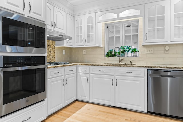 1551 Hutton Pl, Charleston, SC 29407 - kitchen with appliances with stainless steel finishes, under cabinet range hood, white cabinetry, glass insert cabinets, and light stone counters