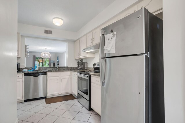 kitchen featuring white cabinetry, stainless steel appliances, dark stone counters, and light tile patterned floors