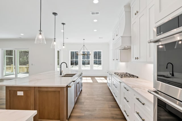 kitchen featuring a kitchen island with sink, stainless steel appliances, wood finished floors, a sink, and visible vents