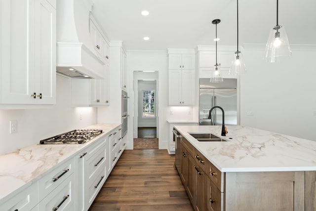 kitchen featuring dark wood finished floors, an island with sink, custom range hood, stainless steel appliances, and a sink