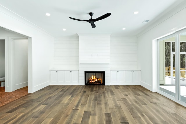 unfurnished living room featuring a healthy amount of sunlight, a large fireplace, wood finished floors, and recessed lighting