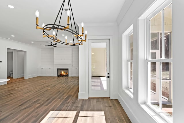 interior space with a fireplace, recessed lighting, ornamental molding, wood finished floors, and baseboards