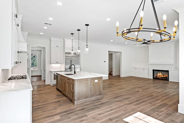 kitchen with visible vents, appliances with stainless steel finishes, open floor plan, wood finished floors, and a sink