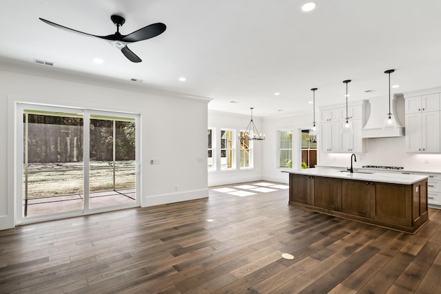 kitchen with dark wood-type flooring, light countertops, premium range hood, a sink, and recessed lighting