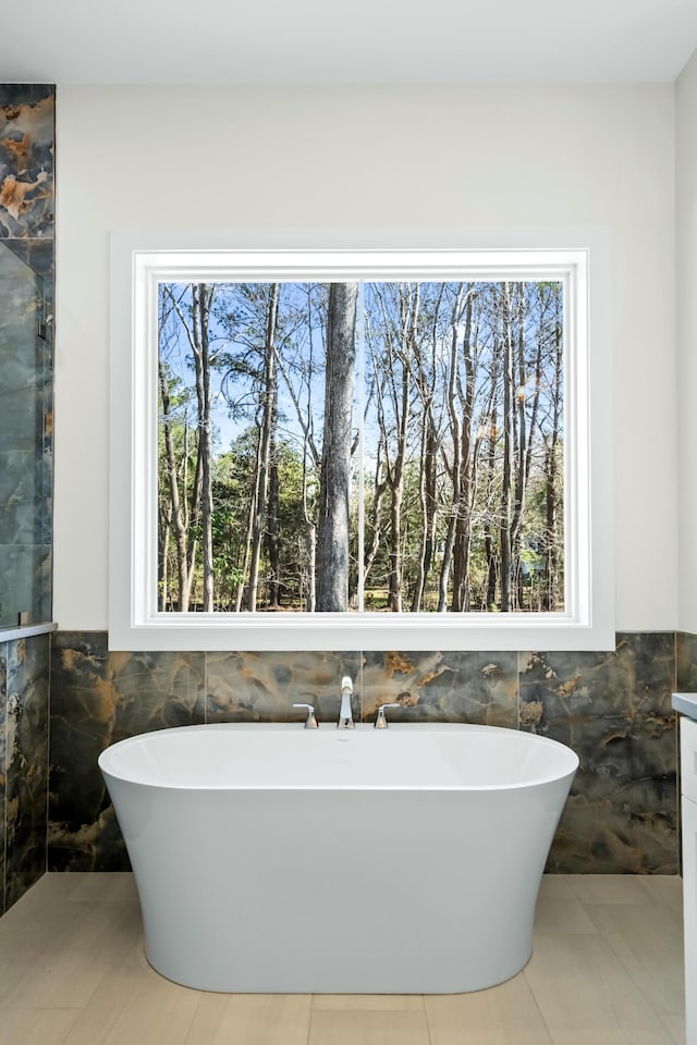 bathroom with a freestanding bath, tile walls, and tile patterned floors