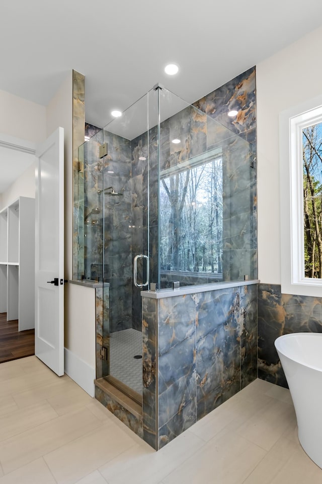 bathroom with recessed lighting, a soaking tub, tile walls, and a marble finish shower