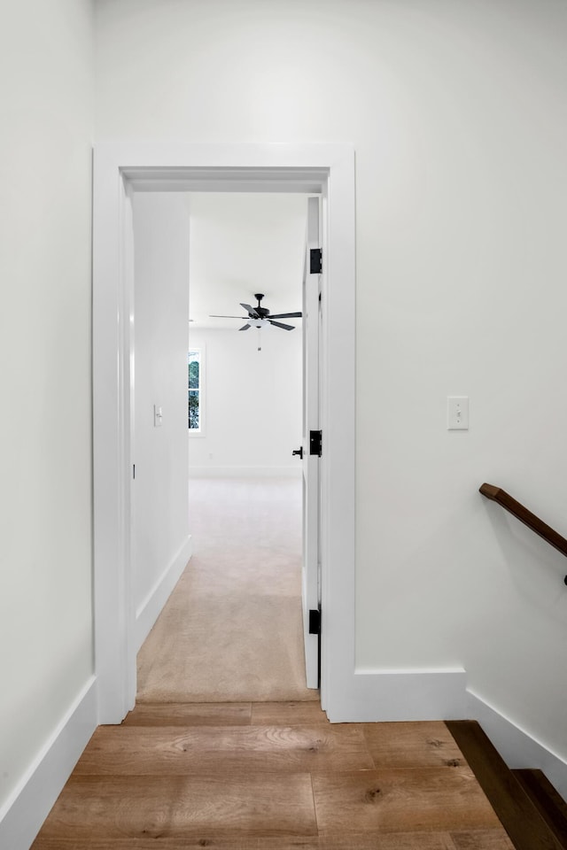 corridor with baseboards and wood finished floors