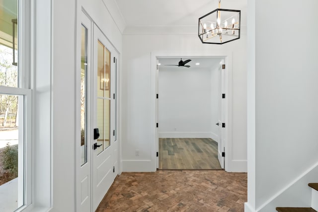 entryway featuring a notable chandelier, baseboards, ornamental molding, and wood finished floors