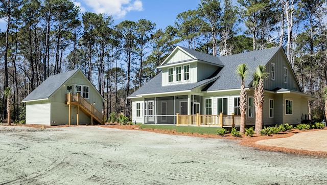 view of front of property with a shingled roof, a sunroom, and stairs