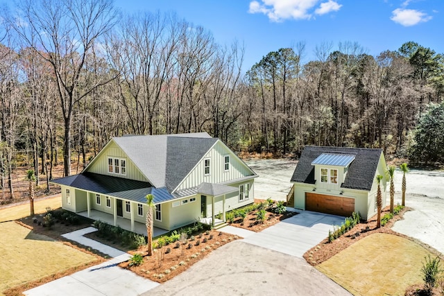 view of front facade with board and batten siding, a standing seam roof, roof with shingles, and metal roof