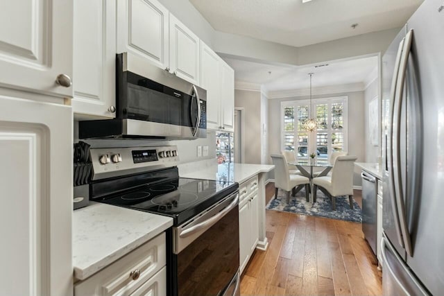 kitchen with appliances with stainless steel finishes, white cabinetry, light wood finished floors, and light stone countertops