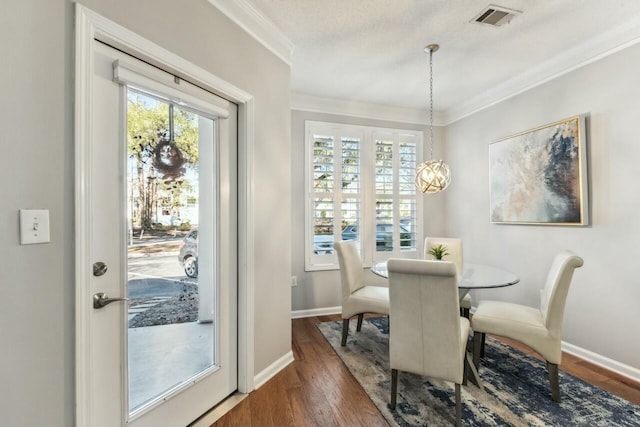 dining area featuring visible vents, crown molding, baseboards, and wood finished floors