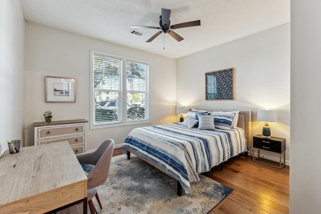 bedroom with hardwood / wood-style floors, a ceiling fan, visible vents, and baseboards