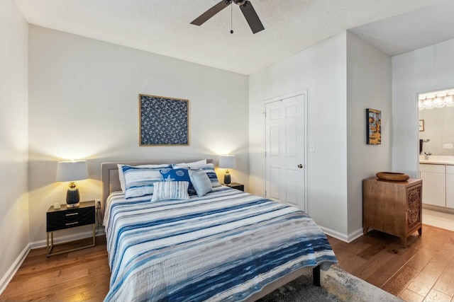 bedroom featuring ensuite bathroom, baseboards, and hardwood / wood-style flooring