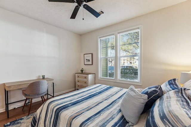 bedroom featuring visible vents, ceiling fan, a textured ceiling, wood finished floors, and baseboards