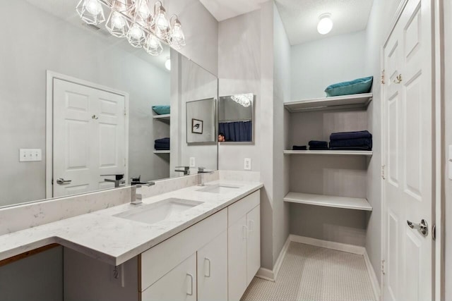 bathroom featuring double vanity, tile patterned floors, a sink, and baseboards