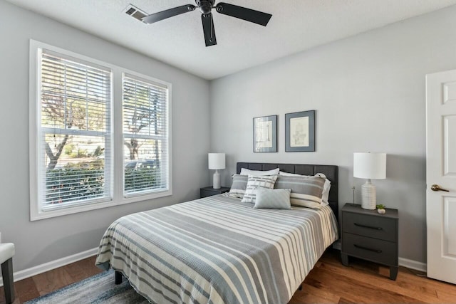 bedroom with visible vents, baseboards, ceiling fan, and wood finished floors