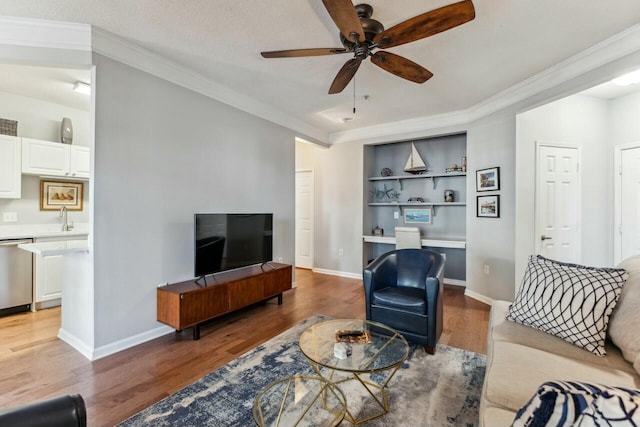 living room with ornamental molding, light wood-type flooring, ceiling fan, and baseboards