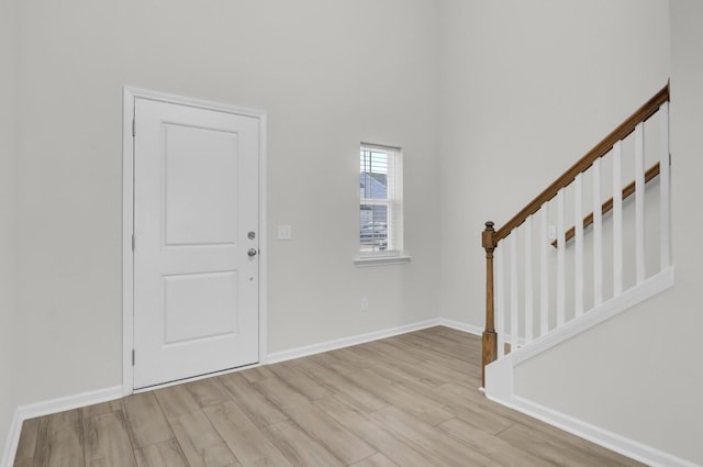 entryway with light wood-style floors, baseboards, and stairway