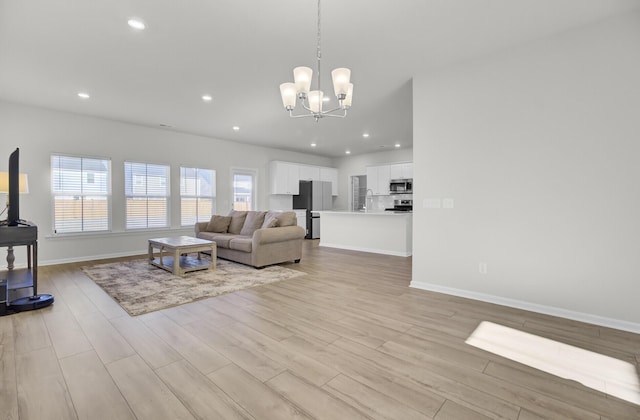 living room with light wood-style floors, recessed lighting, a chandelier, and baseboards