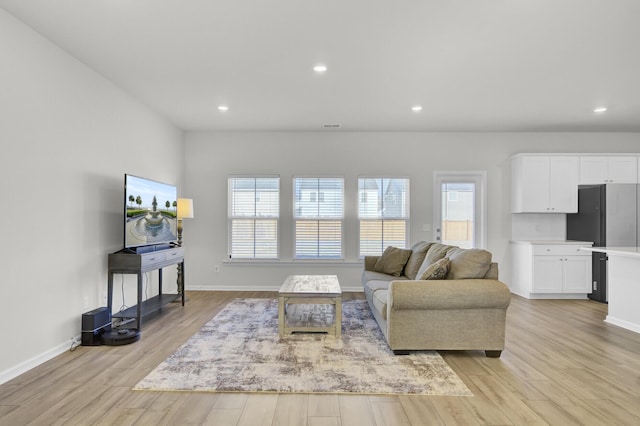 living room with light wood-type flooring, baseboards, and recessed lighting