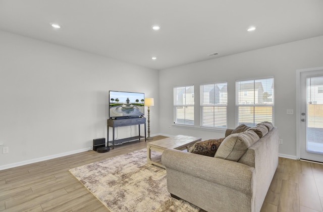 living room with a healthy amount of sunlight, light wood finished floors, baseboards, and recessed lighting