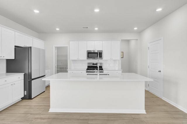 kitchen with a kitchen island with sink, appliances with stainless steel finishes, and light countertops