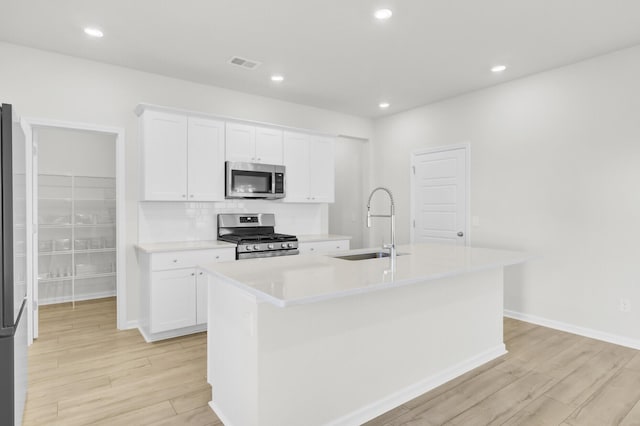 kitchen featuring a center island with sink, visible vents, stainless steel appliances, and light countertops