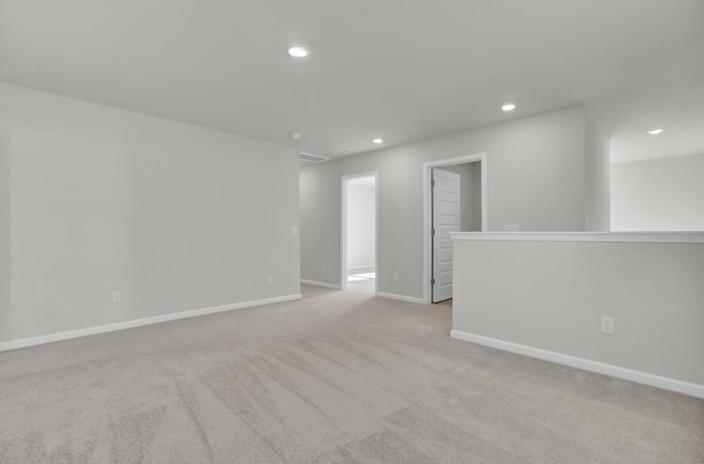 spare room featuring light carpet, baseboards, and recessed lighting