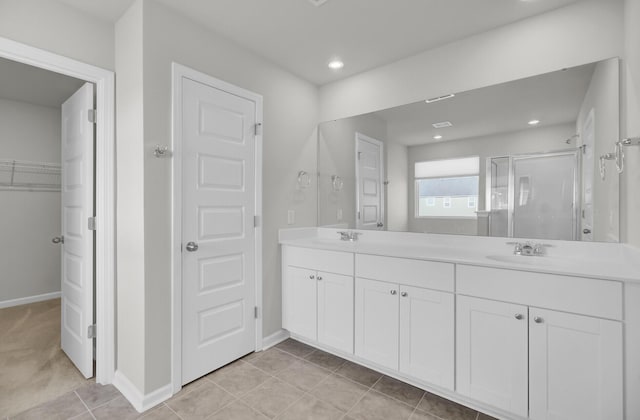 bathroom with a stall shower, a sink, a spacious closet, and double vanity