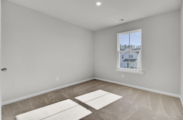 empty room with carpet, visible vents, and baseboards