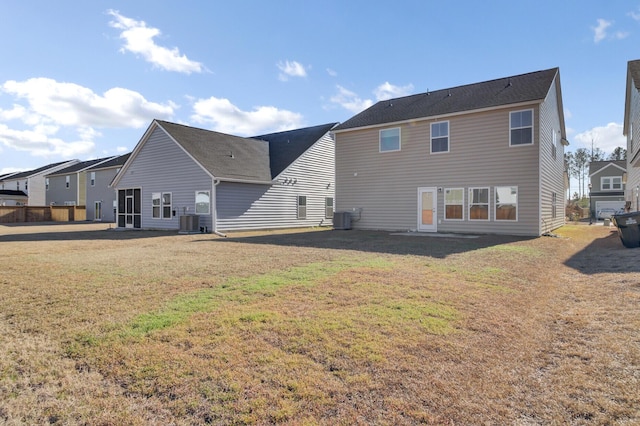 back of property with central AC unit and a lawn