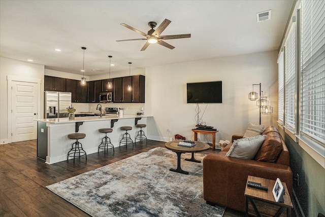 living room with sink, dark wood-type flooring, and ceiling fan