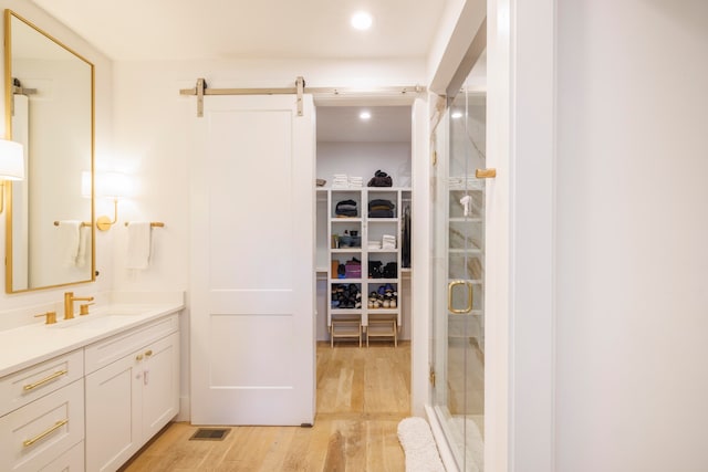 bathroom featuring vanity, an enclosed shower, and wood-type flooring