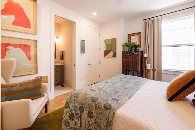 bedroom with ensuite bath and light hardwood / wood-style floors