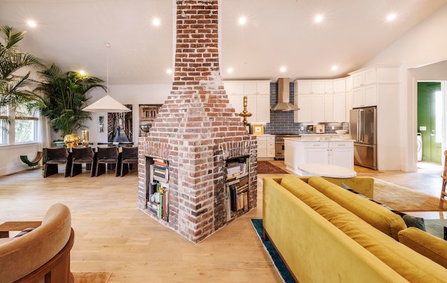 living room featuring washer / dryer, light hardwood / wood-style floors, decorative columns, and lofted ceiling