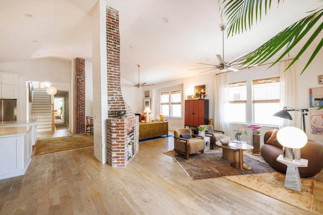 living room featuring ceiling fan, light hardwood / wood-style floors, and vaulted ceiling