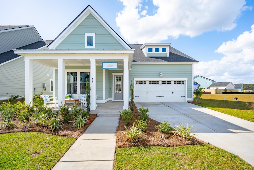 view of front of house with a front yard, a porch, and a garage