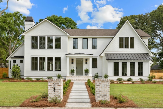 modern inspired farmhouse with a standing seam roof, a chimney, a front lawn, and a shingled roof