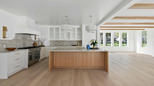 kitchen featuring range with two ovens, custom range hood, light wood-style floors, backsplash, and glass insert cabinets