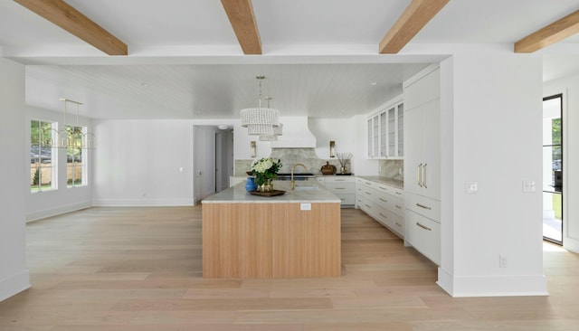 kitchen featuring a chandelier, beamed ceiling, backsplash, healthy amount of natural light, and baseboards