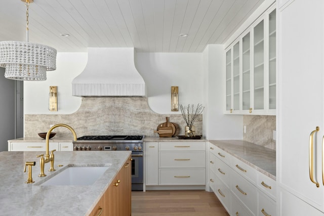 kitchen with custom exhaust hood, high end stove, a sink, wood ceiling, and light wood-style flooring