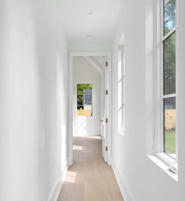 corridor with light wood-style flooring and baseboards
