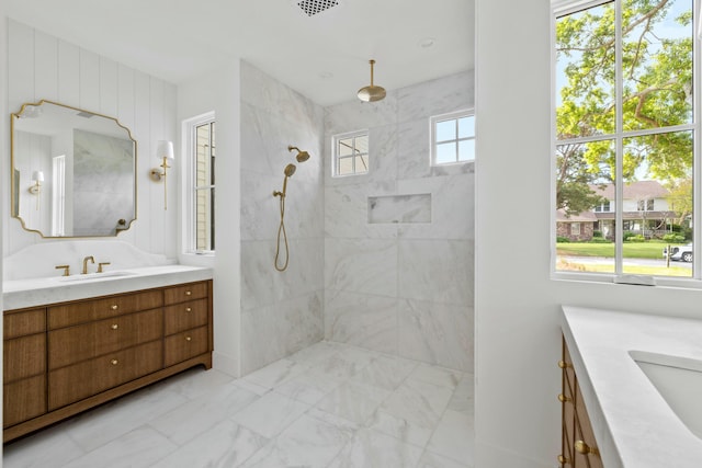 bathroom with vanity, marble finish flooring, and a tile shower