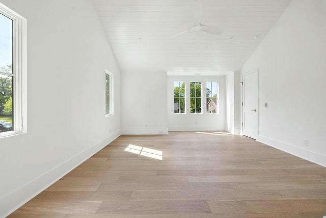 empty room with a ceiling fan, baseboards, light wood-type flooring, and lofted ceiling