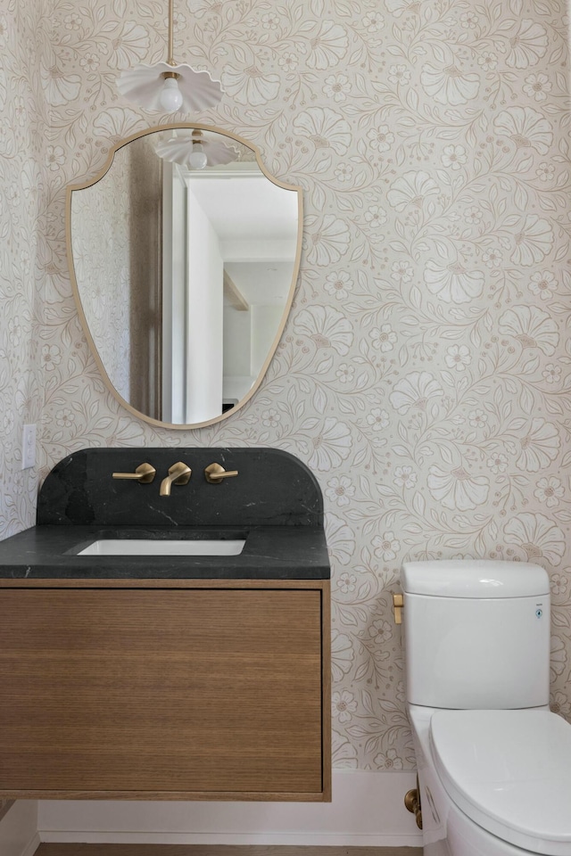bathroom with wallpapered walls, vanity, and toilet