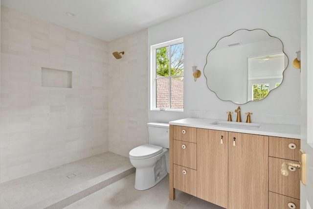 full bathroom featuring tiled shower, toilet, and vanity