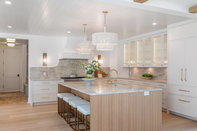 kitchen featuring a sink, a breakfast bar area, light wood-style floors, tasteful backsplash, and recessed lighting