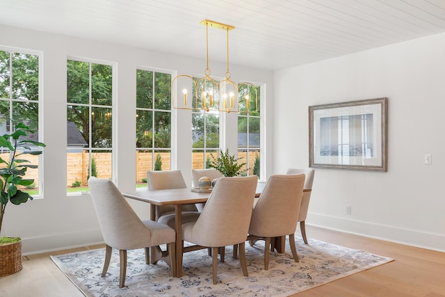 dining space featuring a chandelier, wood finished floors, and baseboards