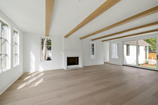 unfurnished living room featuring beam ceiling, a fireplace with flush hearth, light wood-type flooring, and baseboards